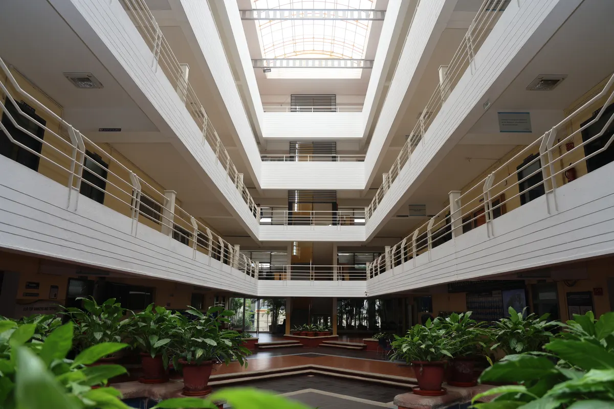 The atrium of the Hebbal campus seen from the ground floor, with plants below and a skylight above.