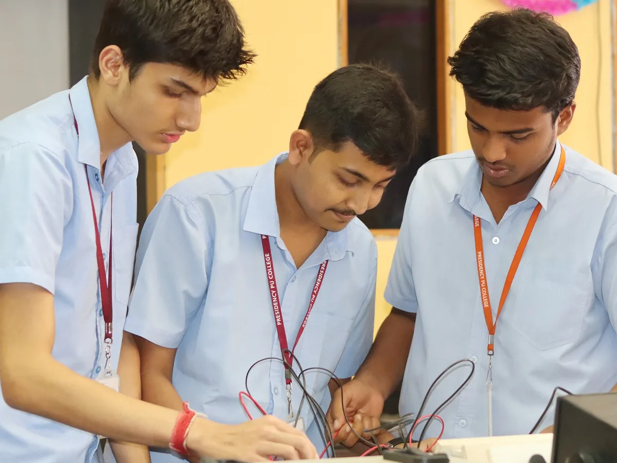 Three students wiring a circuit together at a Physics lab bench.